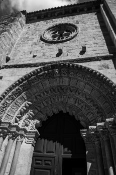 A close-up view of an intricately carved stone archway and doorway of a historic building, showcasing detailed sculptures and a circular window above.